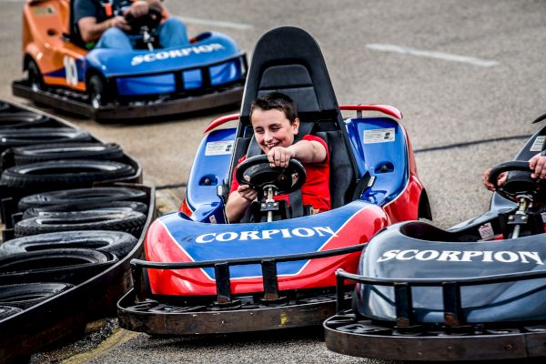 A person is driving a red go-kart labeled 