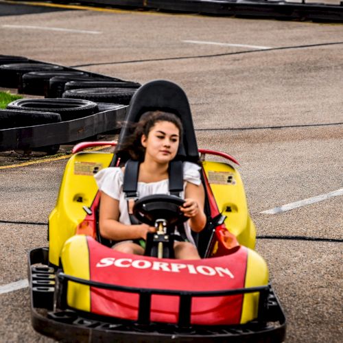 A person is driving a yellow and red go-kart marked 