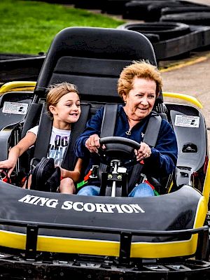 Two people are riding a go-kart labeled 